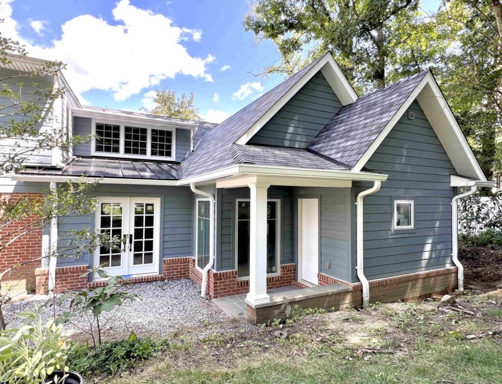 Newly remodeled home with blue siding, pointed brickwork, and new windows and french doors